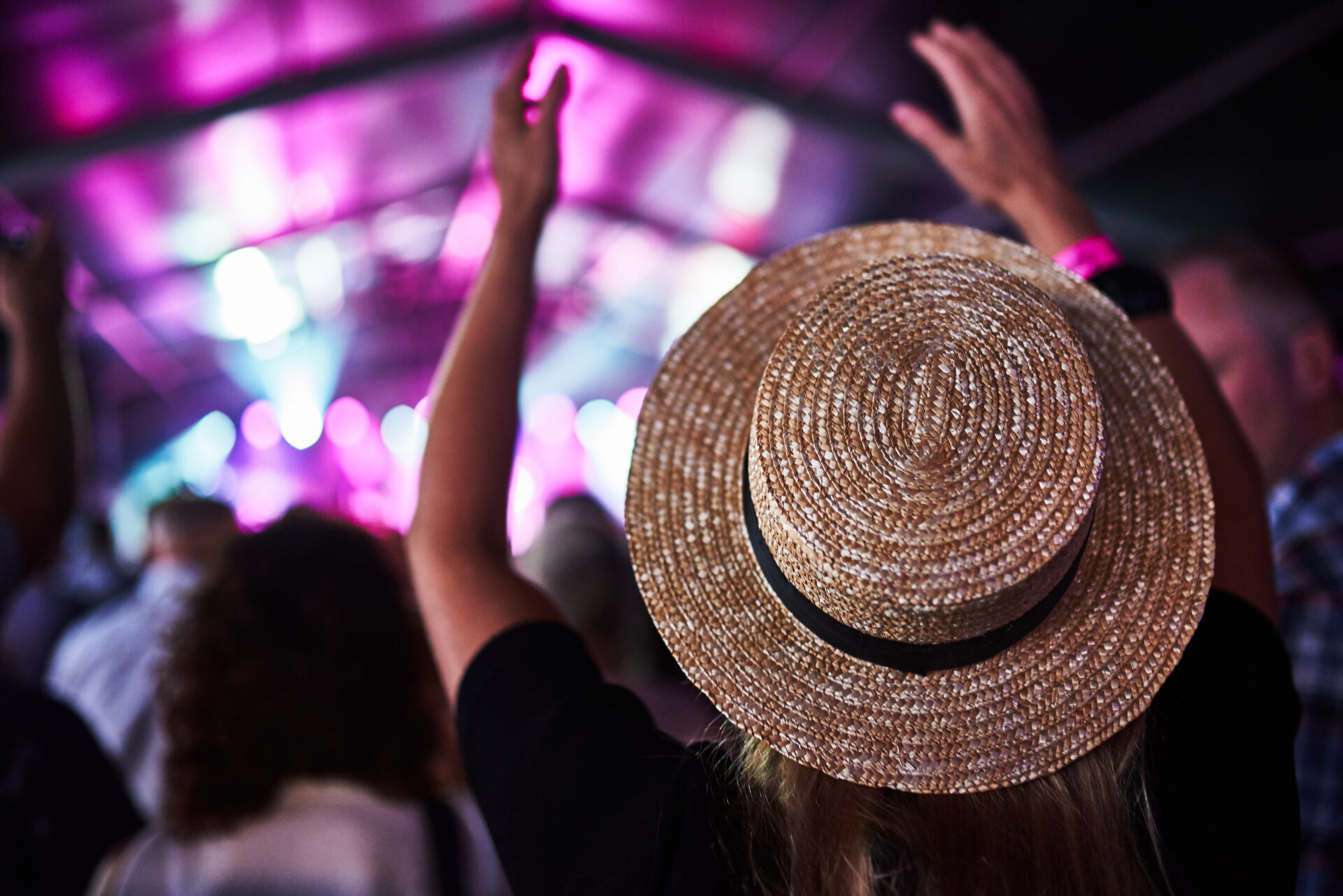 Person in a straw hat cheering at a concert